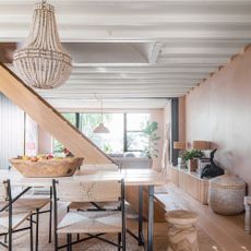 Open plan living dining space with central wooden staircase and bare plaster walls