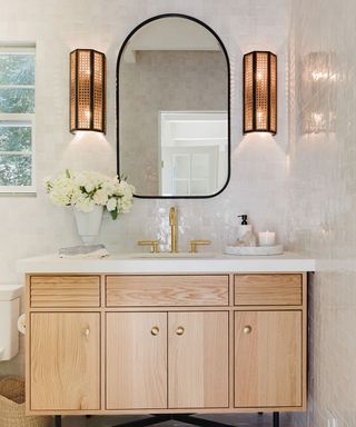 Bathroom with wooden vanity, mirror, two wall sconces