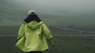 Woman walking away from the camera in the rain wearing a coat