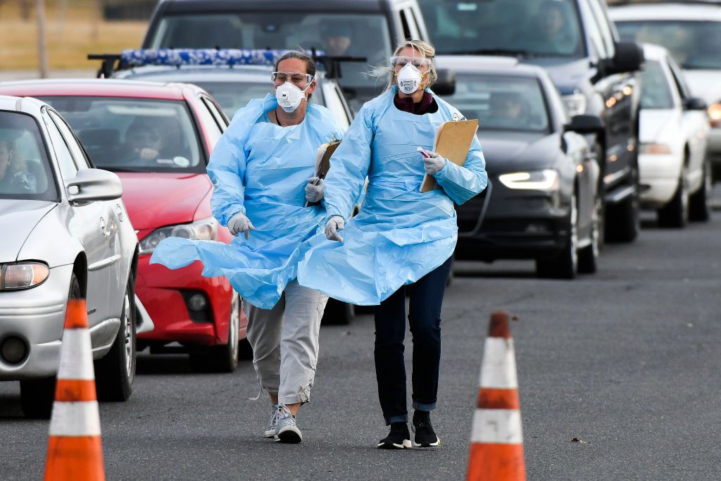 Healthcare workers from the Colorado Department of Public Health and Environment check in with people waiting to be tested for COVID-19 at the state&amp;#039;s first drive-up testing center on March 1