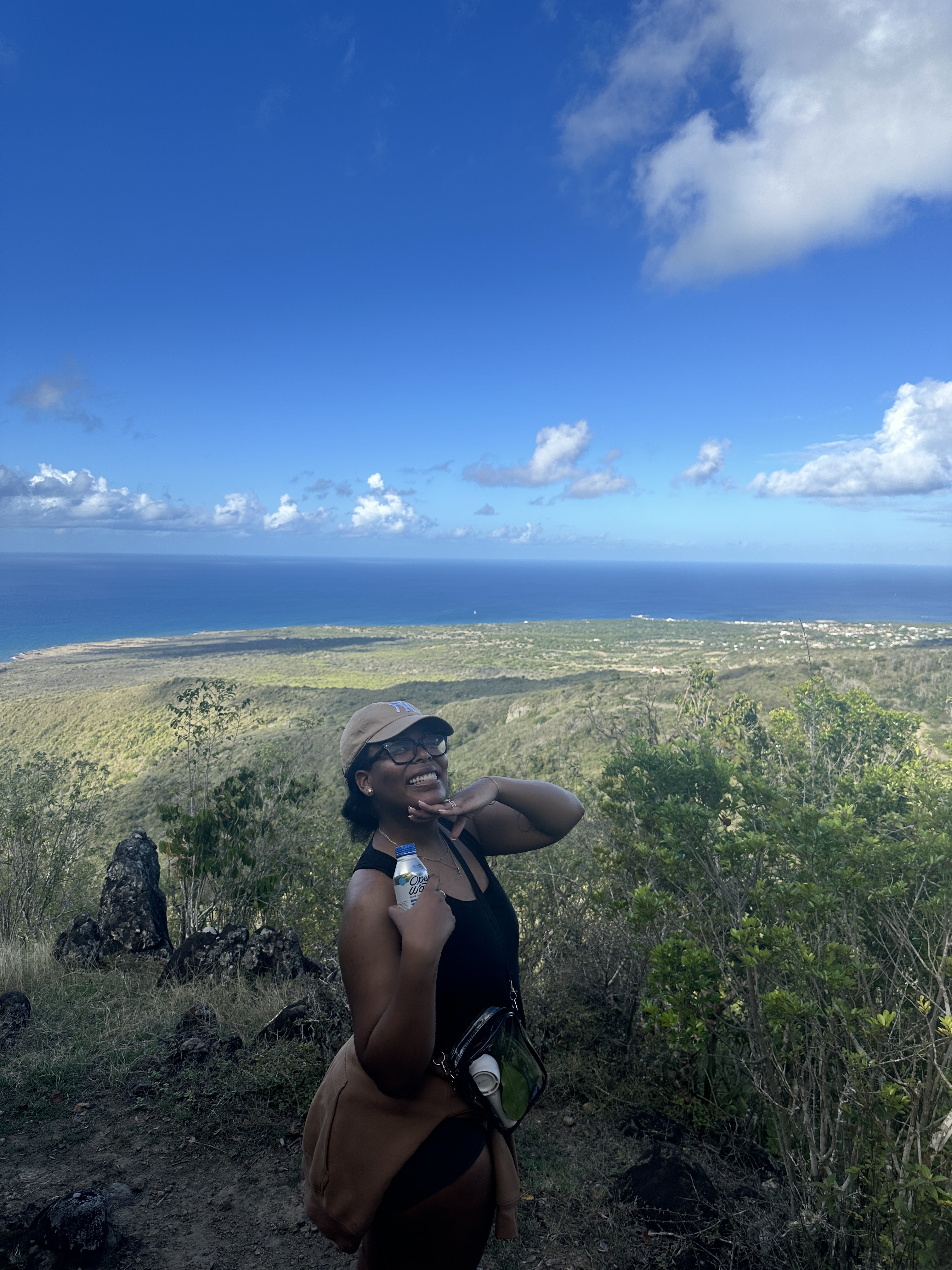 Ariel Baker hiking in Nevis on a mountain covered in greenery next to the ocean