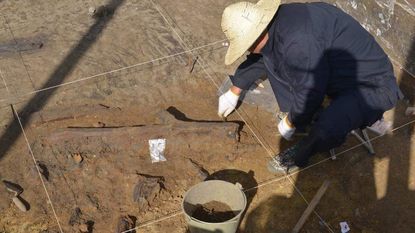 An archaeologist excavating a wooden tool in China.