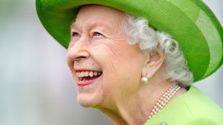 Queen Elizabeth II laughing, wearing a green hat and dress as she attends the Out-Sourcing Inc. Royal Windsor Cup polo match and a carriage driving display by the British Driving Society at Guards Polo Club, Smith's Lawn on July 11, 2021 in Egham, England.
