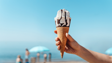 Person holding an ice cream cone in front of the sea