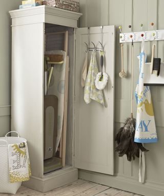 A laundry room with tall beige cabinet housing an ironing board