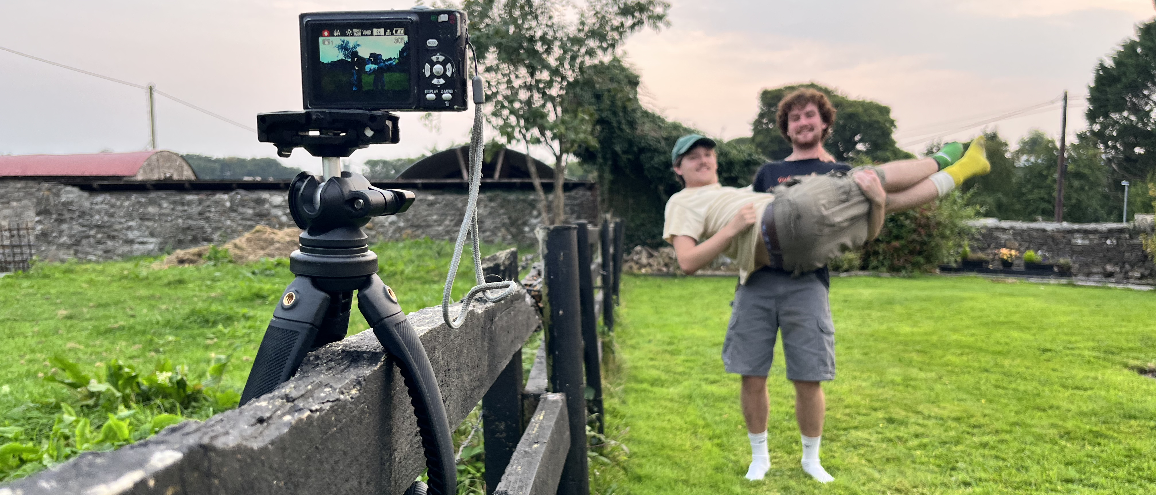 Freewell Vlogpod on a fence with compact camera and two men posing 