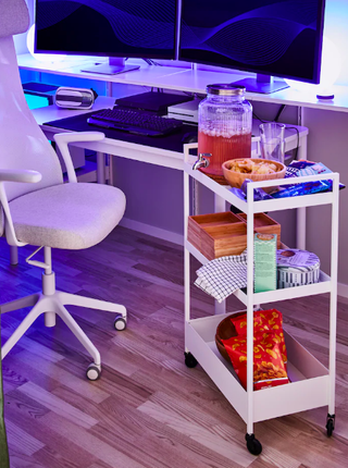 A modern home office with white office chair and rolling utility trolley with assortment of beverages and snacks