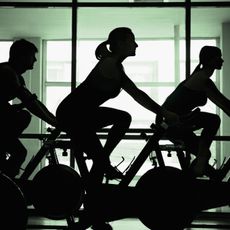 Silhouettes of people on bikes in spin class