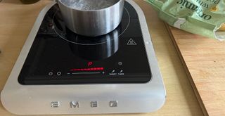Silver Smeg portable induction hob with saucepan