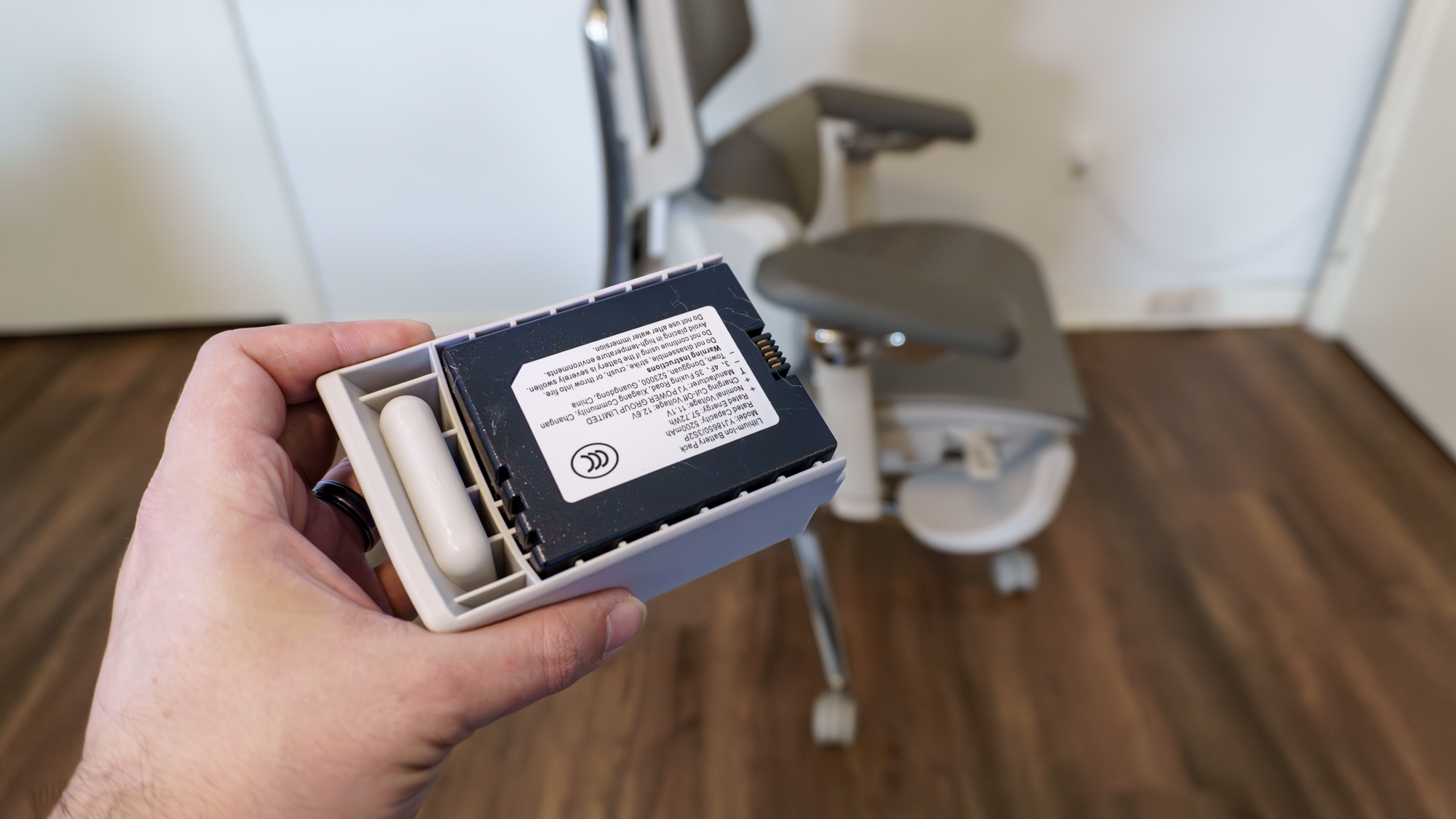 A person holding the battery for the Hbada X7 office chair with it in the background