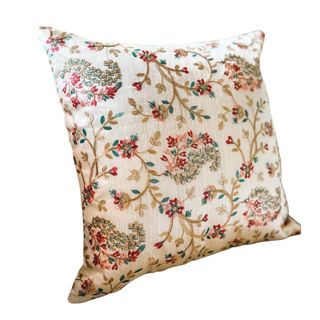 A cream-colored cushion cover with paisley beading and embroidery
