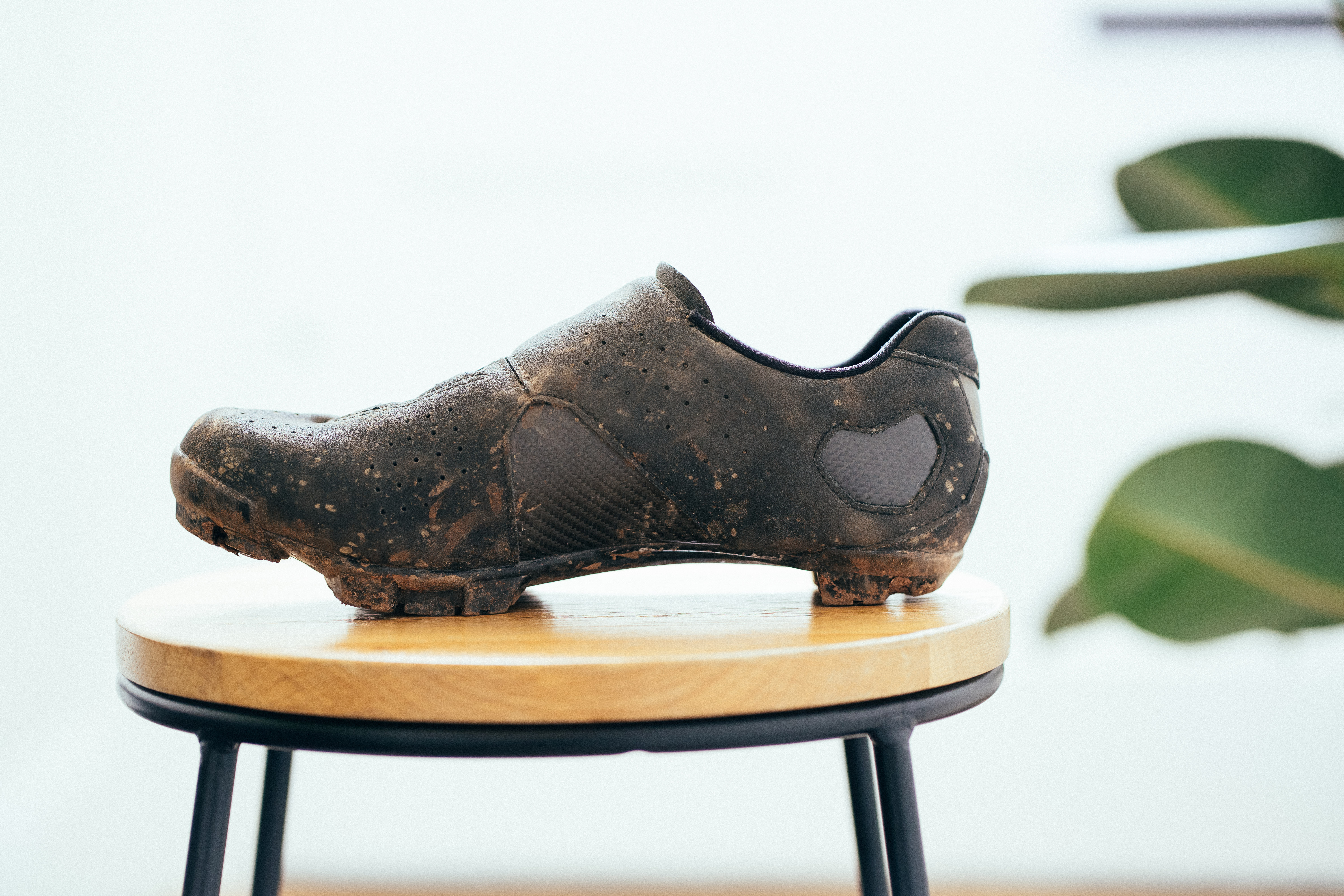 A black gravel shoe on a wooden stool against a white background