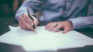 Photo of a man signing a contract. Image: Helloquence on Unsplash