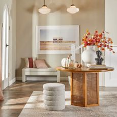 A wooden coffee table and stool with a rug and bench against the wall