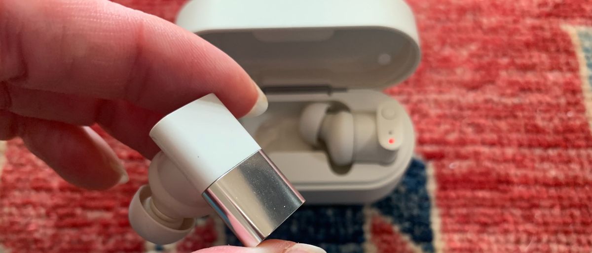 Status Between 3ANC earbud held in a hand, on colorful background