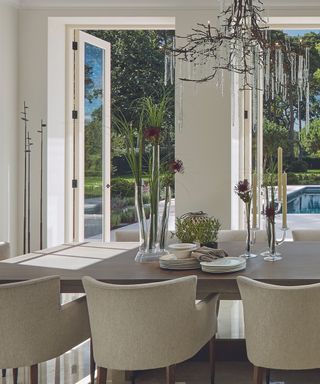 A light-filled living room with floor-to-ceiling glass doors and white upholstered armchairs