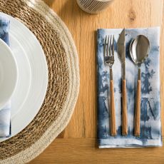 wooden dinning table with kitchen napkin and white plate