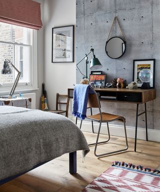 Sophisticated kids' room ideas in a neutral scheme with statement gray wall, midcentury wooden desk and chair and anglepoise lamps.