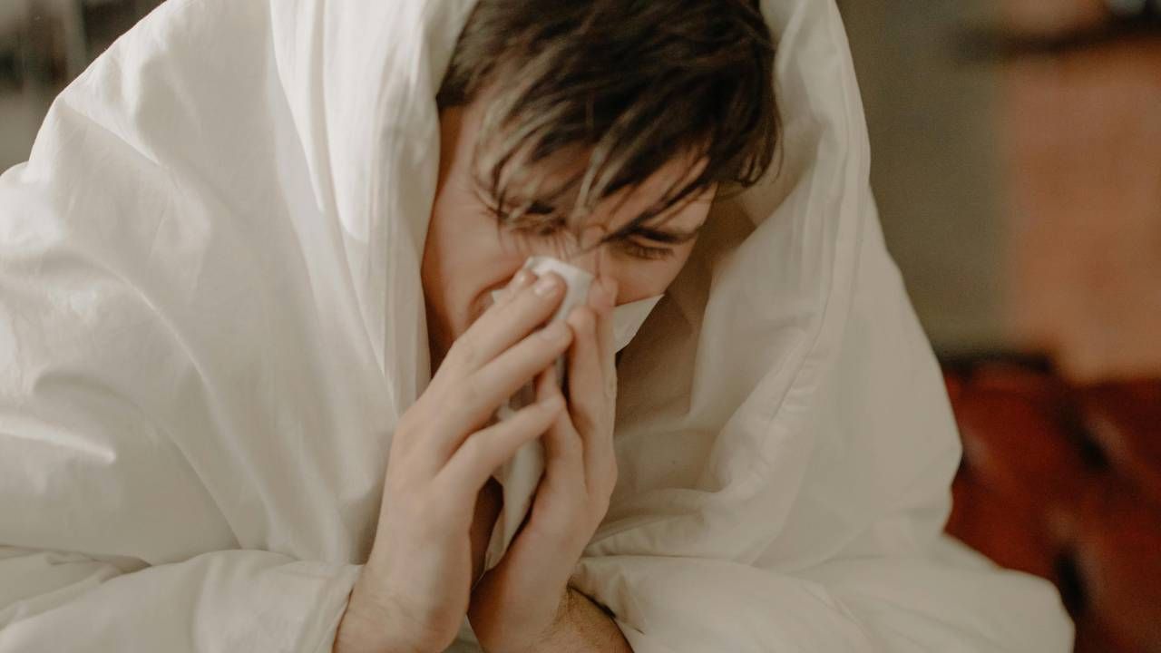  A man wrapped up in a duvet blowing his nose