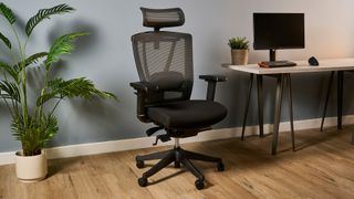 A photo of the Autonomous ErgoChair Pro against a blue-gray wall in an office.