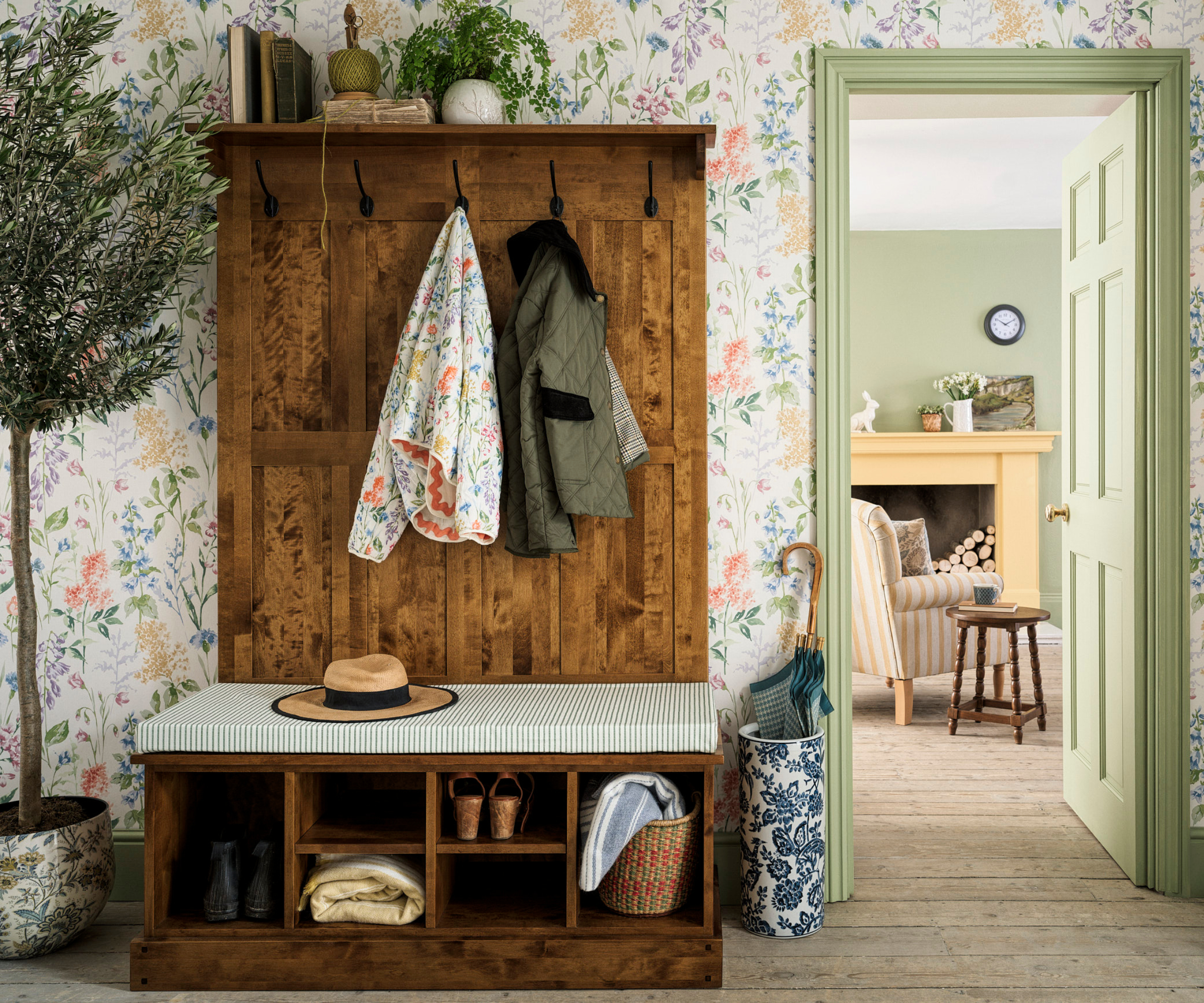 freestanding wooden boot room unit in hallway with floral wallpaper, wooden floor and pale green painted door