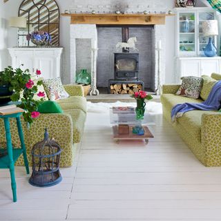 wooden flooring with fireplace and sofa with cushions and glass table