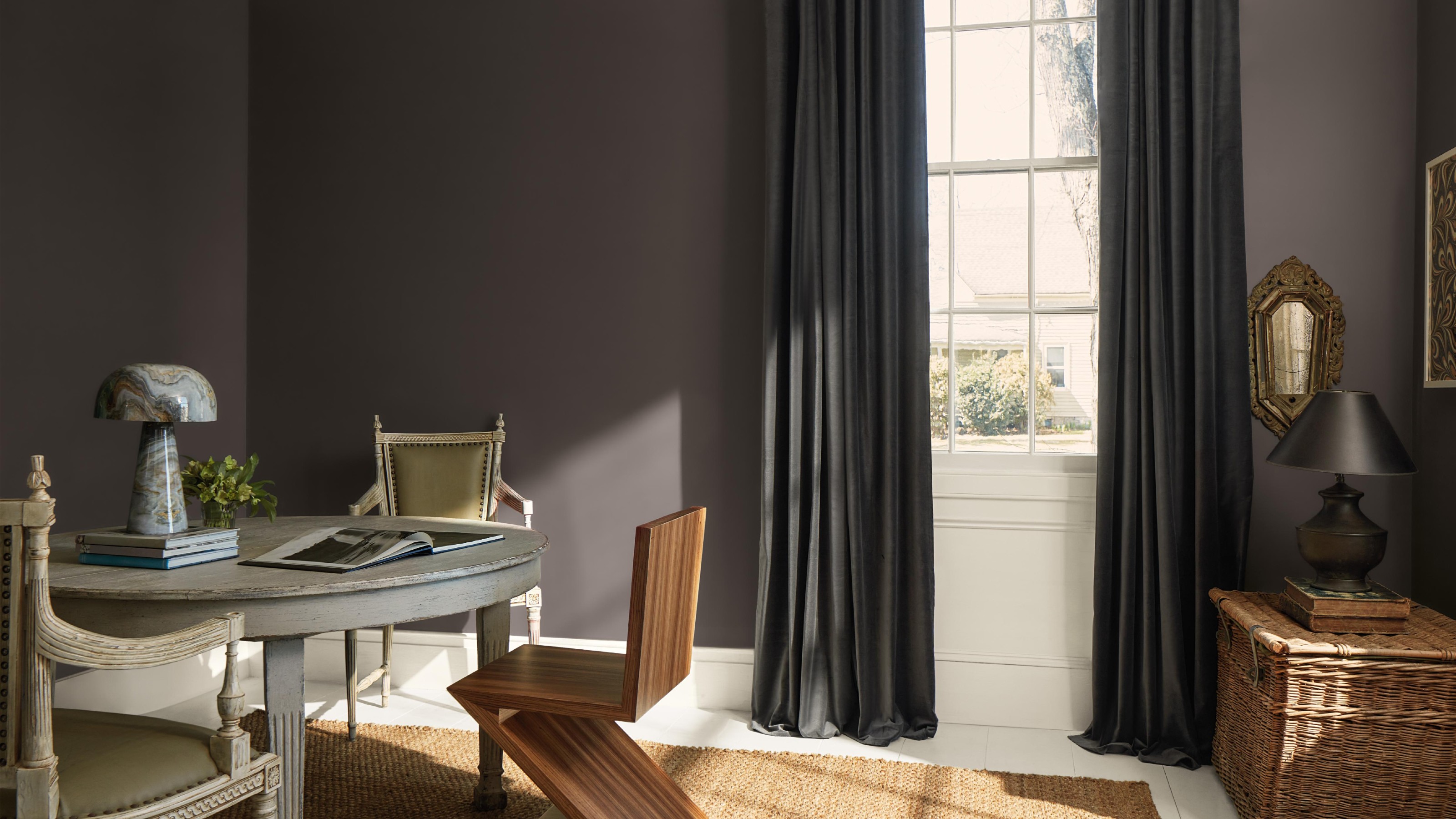 A dining room with mismatched vintage furniture and homewares painted in Benjamin Moore's Silhouette shade, a dark brown with a charcoal undertone