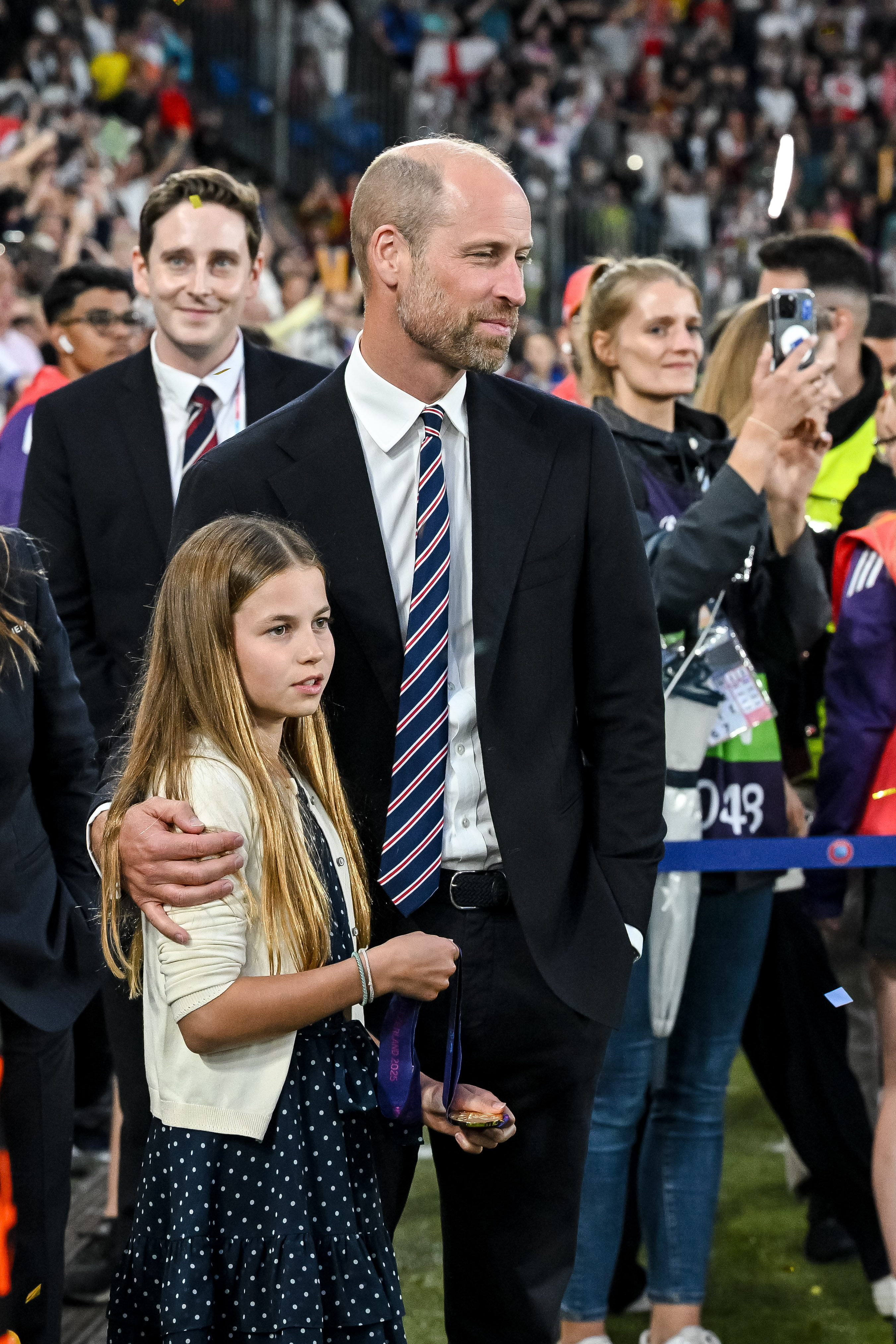 Prince William wears a suit with a red, white, and blue striped tie, and daughter Princess Charlotte wears a navy and white polka dot dress, as the pair attend the UEFA Women's Championship in Switzerland