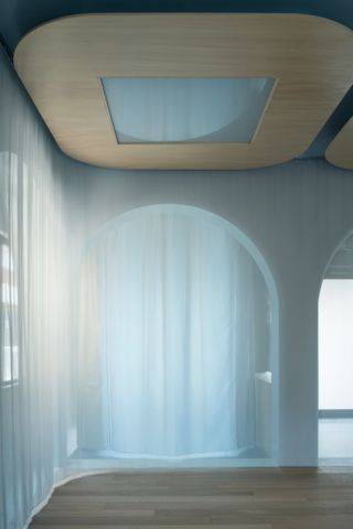 white room with archways and transparent curtains