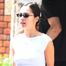 Olivia Rodrigo wearing a white T-shirt, dark-wash jeans, and blue Adidas Tokyo sneakers.