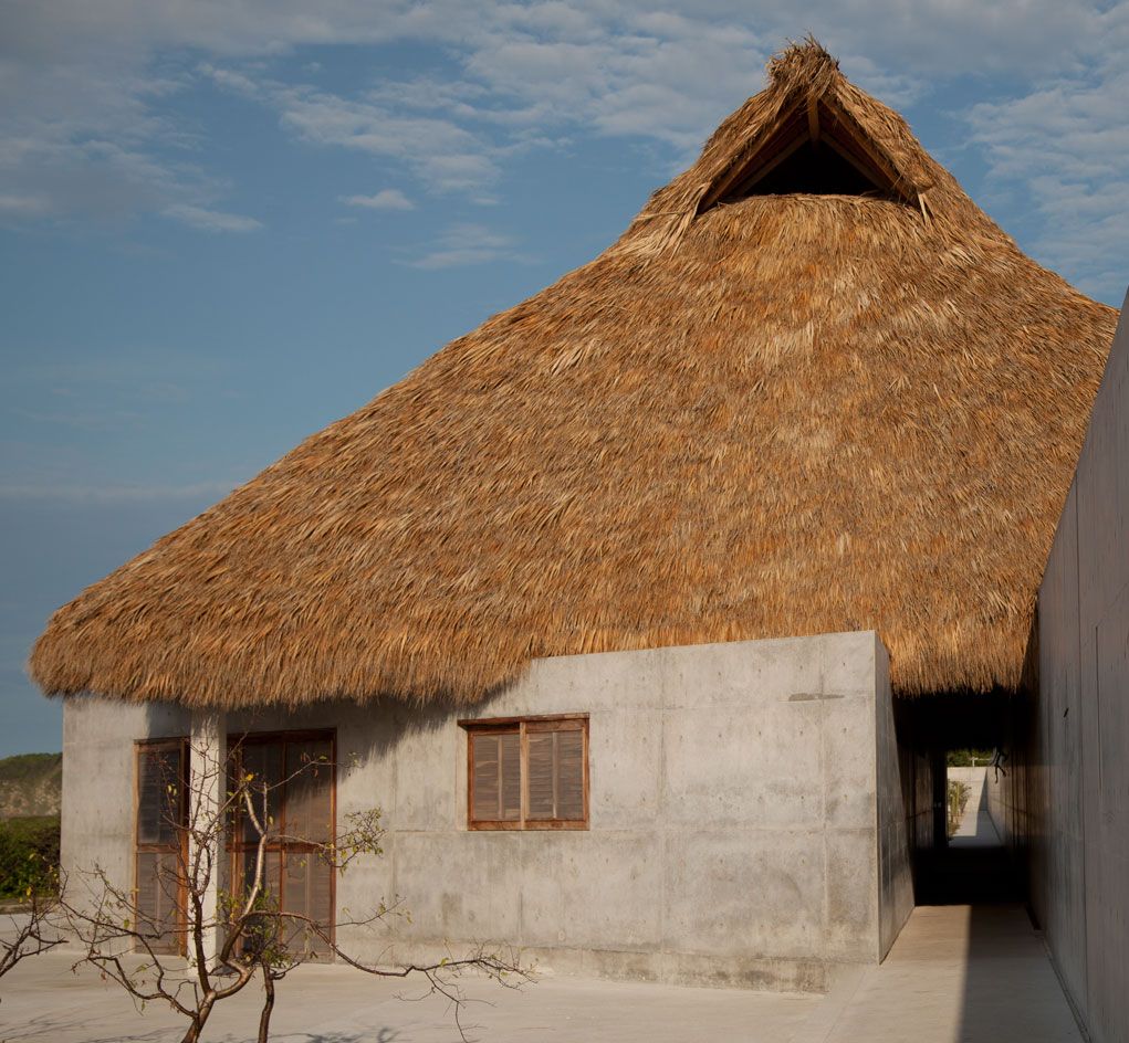 concrete building with grass roof and wooden slat windows and door