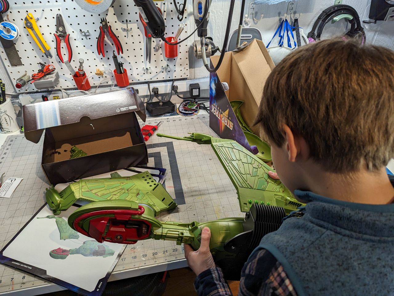 a child assembles a klingon bird of prey on a workbench