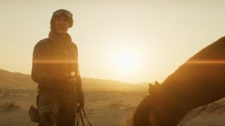 Tom Cruise standing in the desert with a horse at sundown in Mission: Impossible - Dead Reckoning Part One.