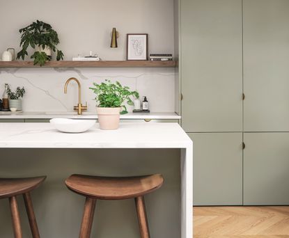 A kitchen with green cabinetry, a white kitchen island, and open shelving 