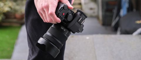 Panasonic Lumix S 28-200mm attached to a camera held in a hand down by a side