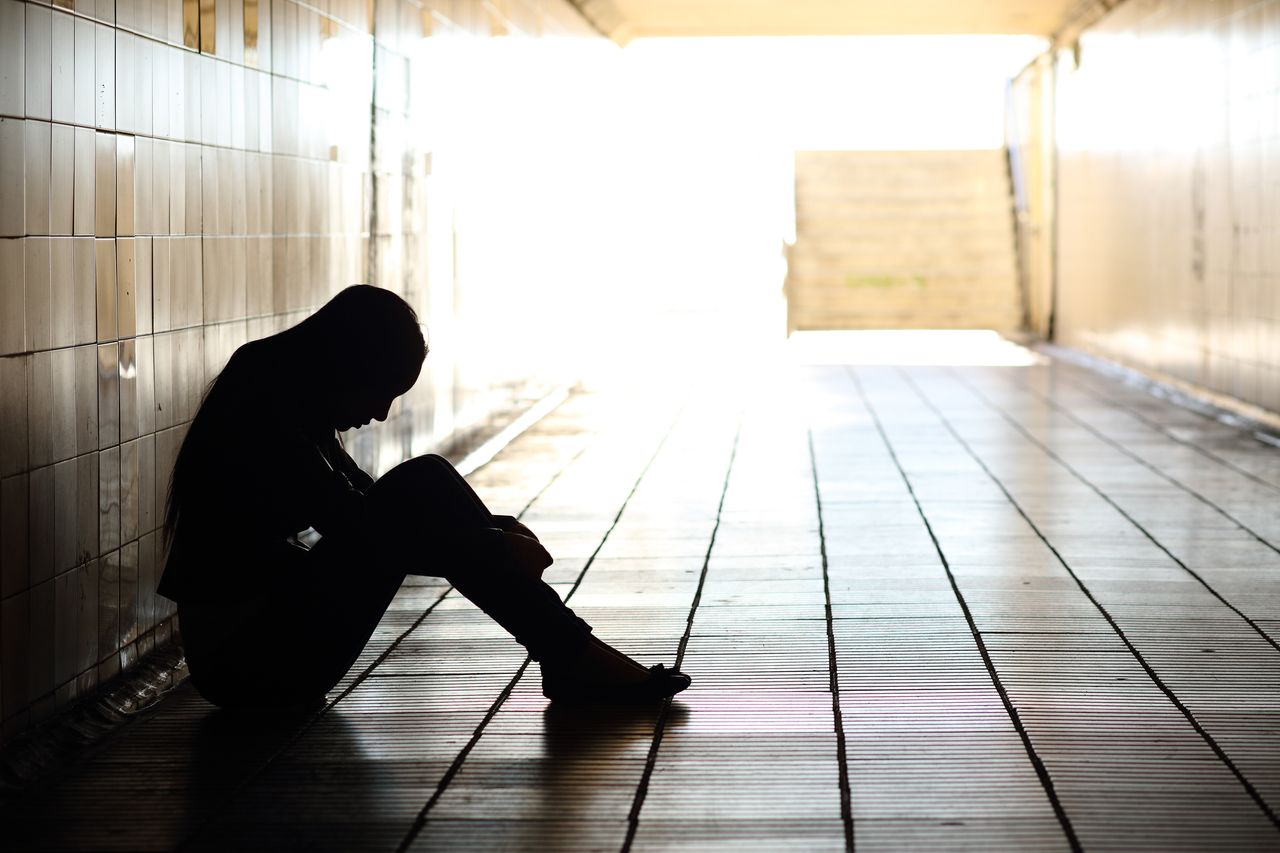 Depressed teenage girl sits in hallway in the dark