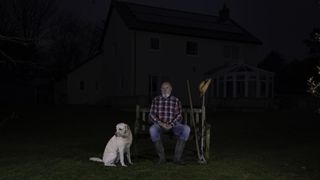 Man outside his house at night with dog
