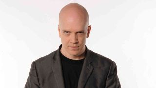 Devin Townsend in a grey suit staring into the camera