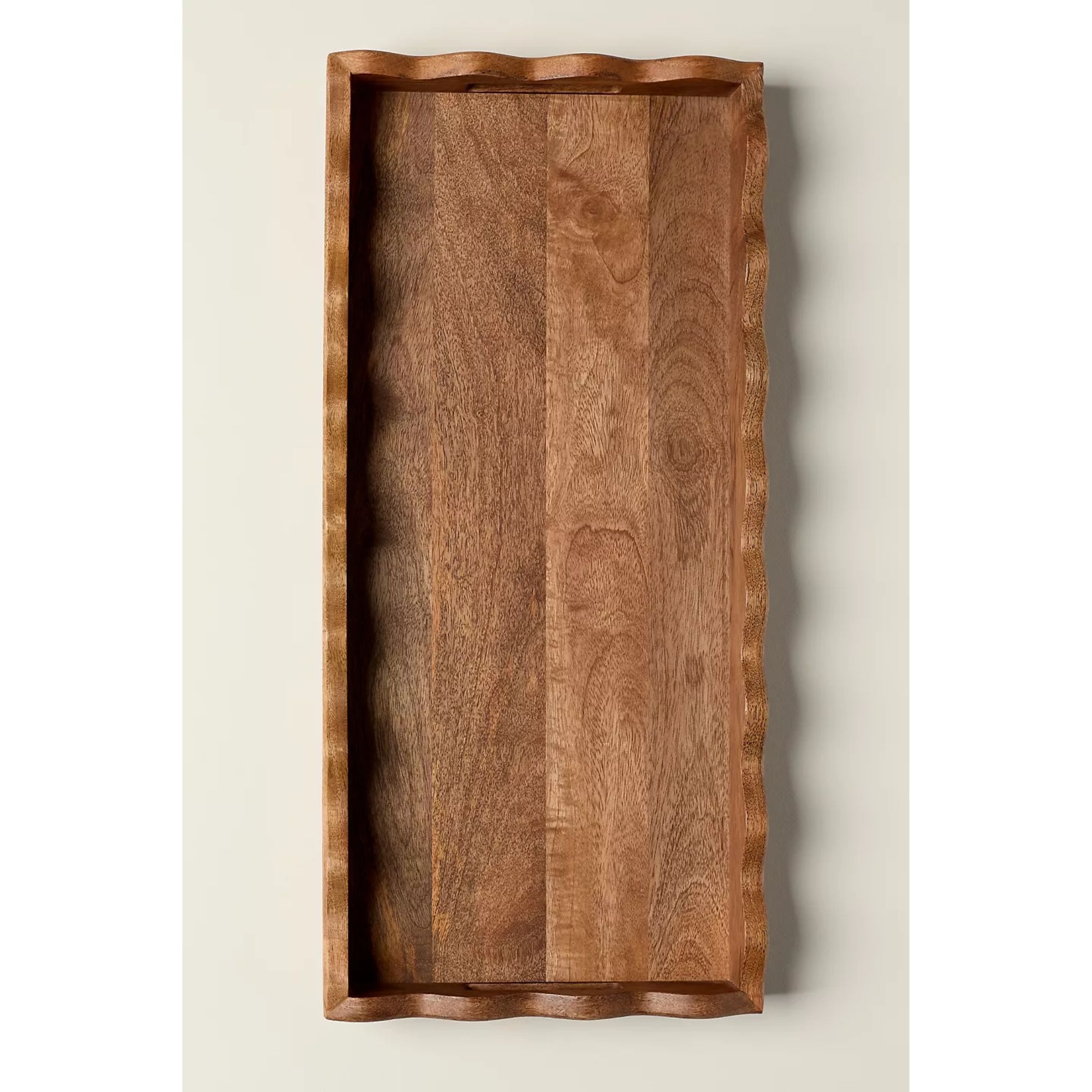 A wooden tray with scalloped edges viewed from above