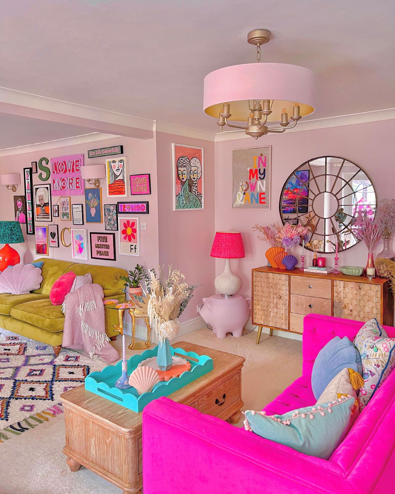 Dining/living room decorated pink with brightly coloured sofas and pillows with a nightstand with pink flowers