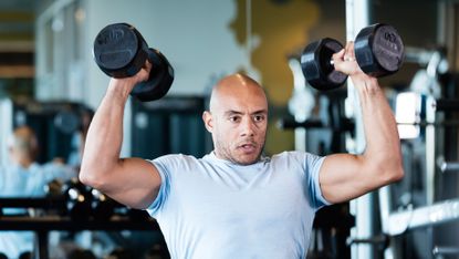 Man training with dumbbells to lose weight and build muscle