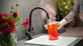 gunmetal boiling water tap pouring steamy water into orange jug