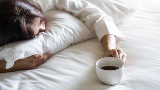 woman asleep holding a cup of coffee