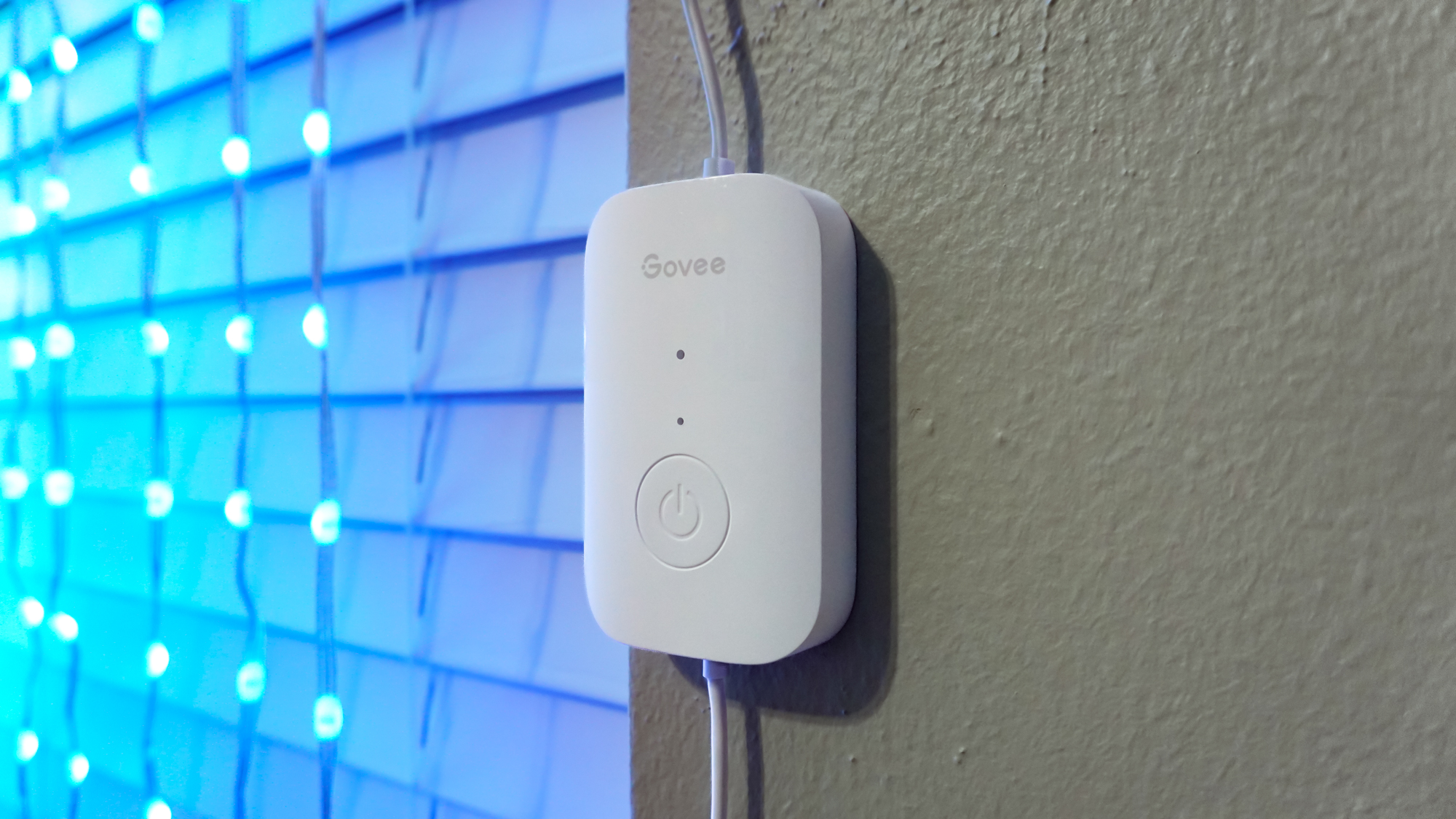 The physical power button that comes with the Govee Curtain Lights Pro installed on a wall next to them