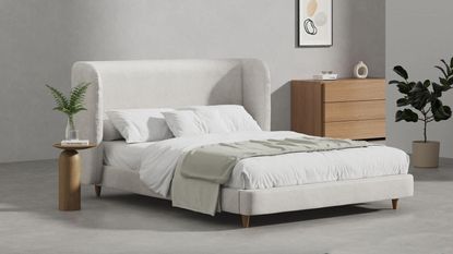 A grey upholstered bed with a curved headboard from Simba