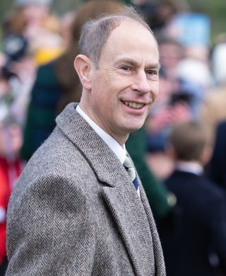 Prince Edward wearing a gray coat walking in front of a crowd on Christmas Day