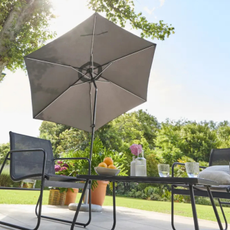 Lidl solar led parasol shading a black metal garden furniture set.