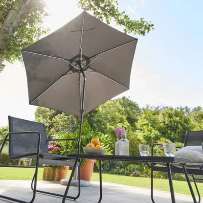 Lidl solar led parasol shading a black metal garden furniture set.