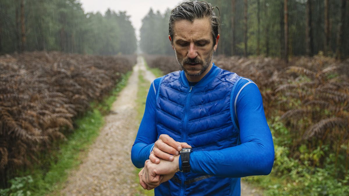 Man checking running watch in the rain