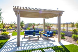 A white wooden pergola shading outdoor furniture on a patio